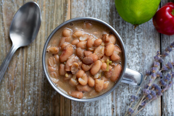 A top down view of a metal cup of cooked pinto beans.