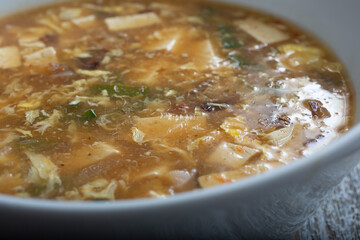 A closeup view of the texture and ingredients in hot and sour soup.