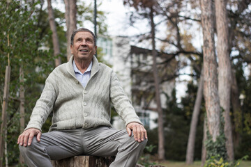 Portrait of happy senior man smiling, in the public park, outdoors. Old man relaxing outdoors and looking up. Portrait of elderly man enjoying retirement