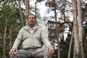 Old man relaxing outdoors with eyes closed. Portrait of senior man looking thoughtful