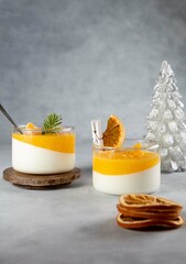 Creamy panna cotta with orange jelly in beautiful glasses and fresh ripe mandarin on white...