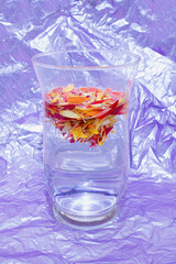 Colorful flower petals in big glass vase on Color of the year 2022 Very Peri background.