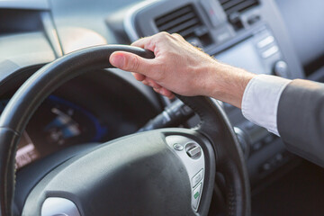 Naklejka premium Close-up hand of businessman man holding car steering wheel