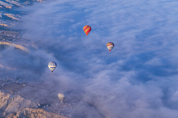 Hot air balloons flying over spectacular Cappadocia. Beautiful view of hot air balloons floating in sunrise blue sky over the mountain landscape of fairy chimneys