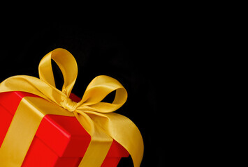 Red gift box with gold ribbon on a black background.