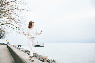 Portrait of beautiful woman spending day outside by lakeside, wearing white clothes