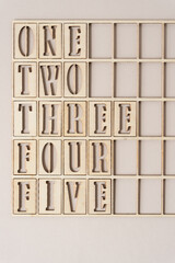 the numbers one, two, three, four, five spelled out and arranged inside a wooden grid