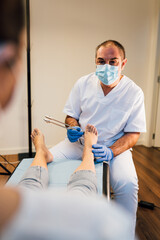 Chiropodist exploring a patient foot with diapason in the medical center
