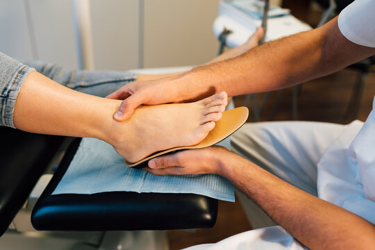 Chiropodist fitting an orthopedic foot insole to a patient.