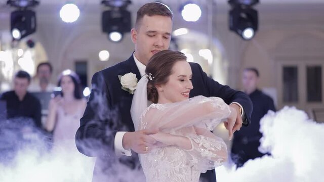 Newlyweds. Lovely Caucasian bride and groom dancing first at the wedding party. Embracing, huggings. Happy family couple. Man and woman in love. Bride in gorgeous wedding dress. Bridegroom in jacket