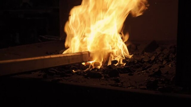 Flamme dans le feu de la forge avec une pi&egrave;ce en acier forg&eacute;. Ferronnerie d'art.