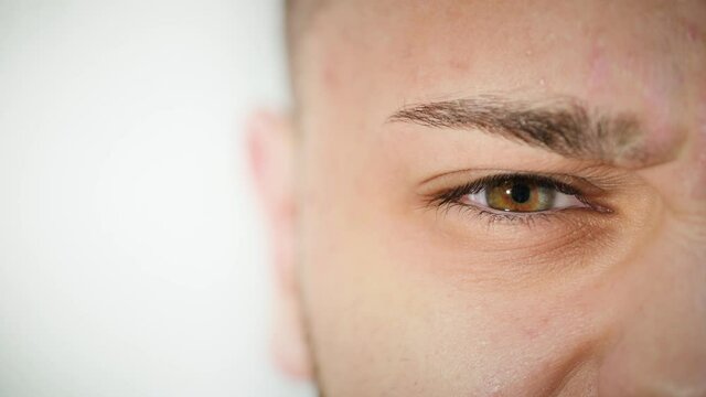 Macro close up of angry man's face with beautiful blue and brown hazel eye. Young Arab male model with different eye colors looking aggressive and disgusted at camera. Slow-motion, 4K.