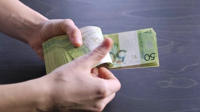4k. Close-up view of counting stack of belarusian 50 ruble paper money. Hands hold and count a lot of cash. Saving. National currency of Belarus. Credit liabilities. Profit. Big debt. Taxes payment.