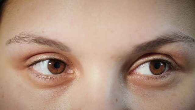 Close up of face of young Arab woman. Girl looking around with brown eyes. Macro portrait of female middle eastern Muslim model with smooth skin moving her eyes from one side to another. 4K.