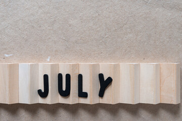 the month of july arranged on a wooden object