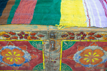 An old, decorative, painted colored chest. Cloth upholstered chest.