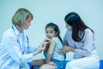 Female doctor holding a syringe containing vaccine against disease at the hospital to inject children have a mother to support