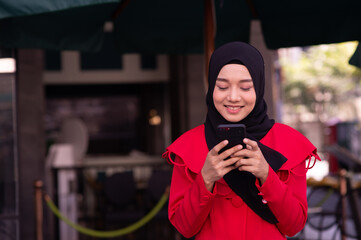 Muslim woman is happy to chat messages via smartphone.