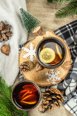 Hot black tea and lemon with winter decor. Cozy sweater, fir tree branches, nuts, snowflakes