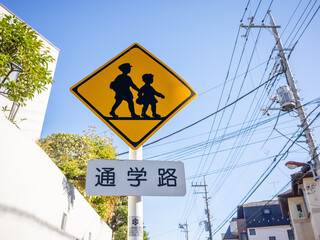 yellow road sign with silhouettes of kids on the street to notice the school road in tokyo