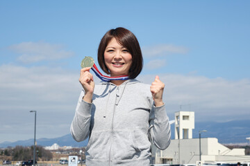 メダルを手に持つ優勝した女性　日本人　女性
