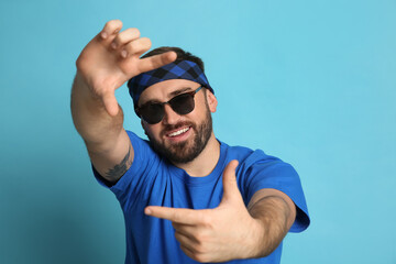 Naklejka premium Fashionable young man in stylish outfit with bandana on light blue background