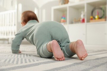 Cute baby crawling on floor at home, back view