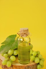 Grape seed oil.Base cosmetic oil for massage and care for face and body. bottle and bunch of grapes on a bright yellow background.Organic Natural Bio Grape Seed Oil.natural cosmetics