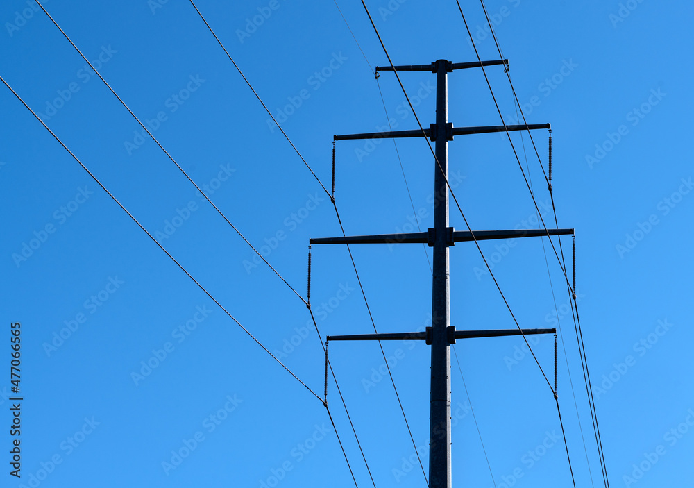 Wall mural high voltage power line towers shot from below on a sunny day and blue sky.