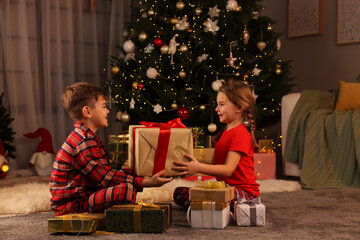 Obraz na płótnie Canvas Cute little children with gift box near Christmas tree at home