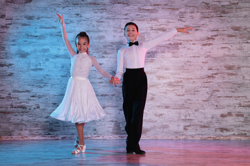 Beautifully dressed couple of kids dancing together in studio