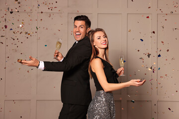 Happy couple with glasses of sparkling wine celebrating New Year indoors