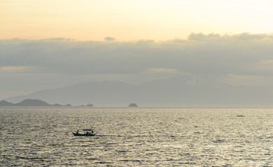 A gorgeous sunset over the Pacific Ocean with rain over the outlying islands and puffy clouds. 