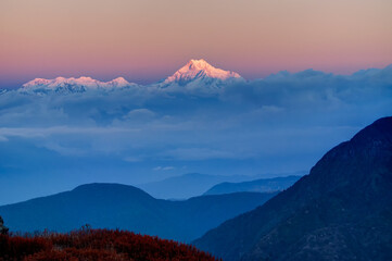 Beautiful first light from sunrise on Mount Kanchenjugha, Himalayan mountain range, Sikkim, India. Blue coloured clouds surrounded the mountains at dawn