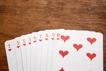 Playing cards with heart symbols on a wooden table