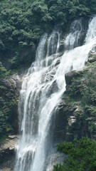Fototapeta premium The beautiful countryside view with the waterfall flowing in the mountains after the rainy day