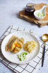 a plate of pempek kapal selam served with noodles and sauce named cuko, it is a traditional cuisine from Palembang, Indonesia