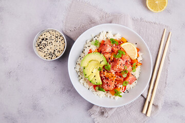 Poke bowl with salmon or tuna, rice, avocado, sesame seeds, micro greens. Hawaiian diet food with fish, pokebowl. Top view. 