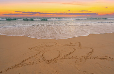 Fototapeta na wymiar Happy New Year 2022, Lettering on the beach with waves and sunset sky Numbers 2022 year on the seashore, Message hand written in the golden sand on beautiful sunset or sunrise golden sky background