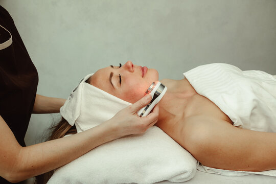 Beautician doing led light therapy to woman with problematic skin in SPA