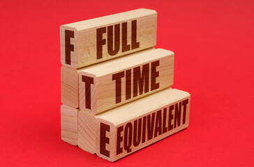 On a red background, wooden blocks with the inscription - full time equivalent