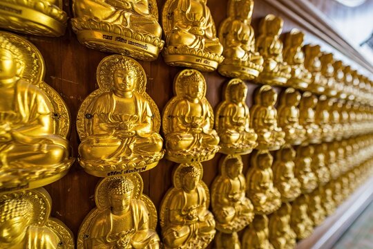 Bangkok, Thailand - December, 20, 2021 : Many golden buddha statues arrange by row and column at the wall in Wat Leng Nei Yee 2 Temple at Bangkok, Thailand.