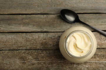 Jar of delicious mayonnaise and spoon on wooden table, flat lay. Space for text