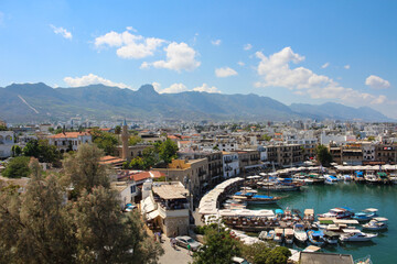 Fototapeta premium KYRENIA . CYPRUS.View from the fortress on the Cyrenian Harbor, houses of Kyrenia, mountains and blue sky with clouds...