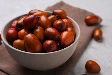Fresh Ziziphus jujuba fruits with bowl and napkin on table, closeup