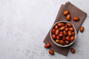 Fresh Ziziphus jujuba fruits with bowl and napkin on light table, flat lay. Space for text