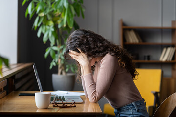 Exhausted upset woman sit at desk hide face in hands tired of difficult tasks. Stressed frustrated female employee feel headache work overtime suffer from burnout at workplace. Stressed businesswoman - obrazy, fototapety, plakaty