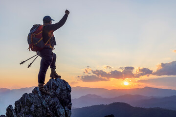 Silhouette Successful hiker outstretched arms with holding stick on mountain top cliff edge at...