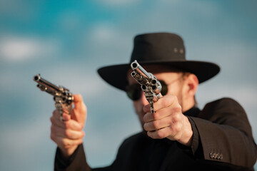 Sheriff in black suit and cowboy hat shooting gun, close up western portrait. Wild west, western,...
