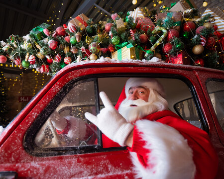 Portrait of santa claus driving a red car for christmas.